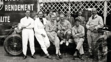 Group of gentlemen posing along side a Bentley