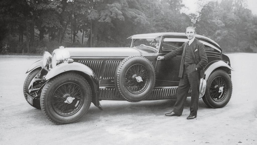 Bentley Speed Six Coupe, side angled view with Walker Owen posing with it and trees in backdrop.