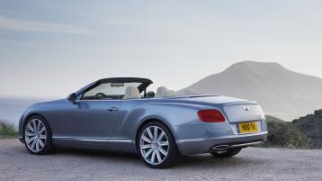 Bentley Continental GTC, in Silverlake colour featuring 21 inch wheels, parked on top of hill with sea in view.