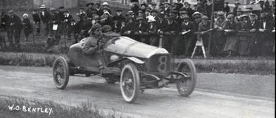 Legendary Bentley DFP driving along a racetrack with spectators in the background