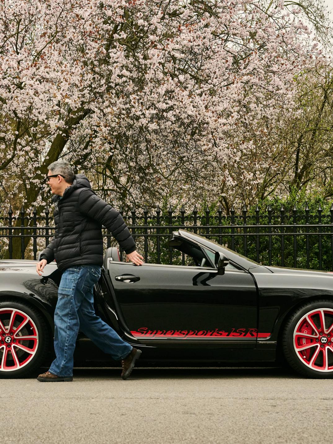 Chart Chirathivat exiting his Bentley Supersports ISR, which is parked at the side of the road.