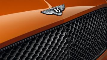 Front end of Bentley Continental GT Speed in Orange flame featuring Dark tint radiator matrix and Bentley Wing badge on bonnet.