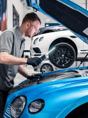 A Bentley technician with LED torch carrying out engine checks on Bentley Continental GT 