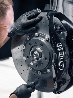 Bentley technician working on Ceramic brakes with Bentley Branded brake black brake callipers.