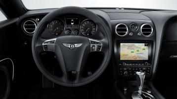 First Generation Bentley Continental GT driver side view, with mono tone steering wheel and center console in view featuring advanced infotainment system.