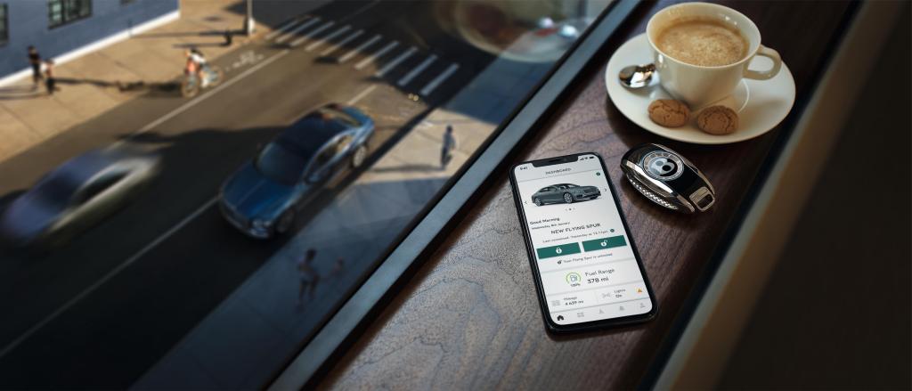 Smartphone featuring My Bentley App and Bentley Key fob in view with a cup of coffee