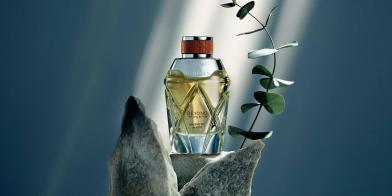Close up of Bentley fragrance Magnetic Amber bottle with decorative leaves and stones.  