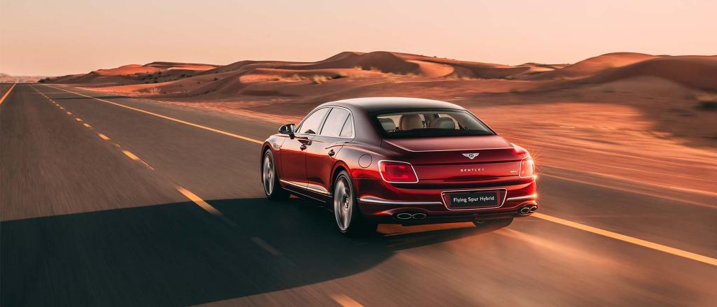 Side view of Bentley Flying Spur Hybrid in St.James Red (Solid) being recharged by Bentley branded PHEV home charger.