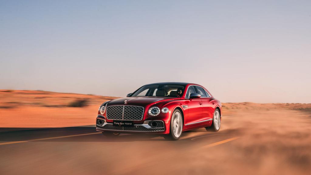 Bentley Flying Spur Mulliner in St.James Red (Solid) colour featuring Chrome Matrix griller with black surround driving along a desert road.