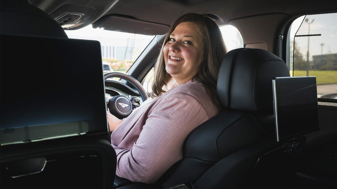 Sina sat in the driver's seat of a Bentley.