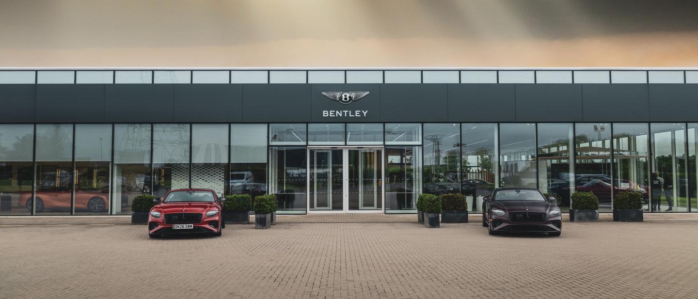 Six visitors entering Bentley CW 1 house in glass exterior, with rear view of Bentley Bentayga in Beluga colour