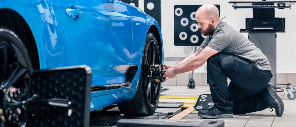 Technician working on front right wheel of Bentley Continental GT.