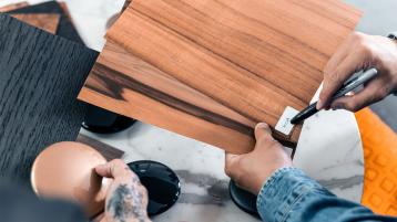 A craftsman holding Oper Pore Koa Veneer sample.