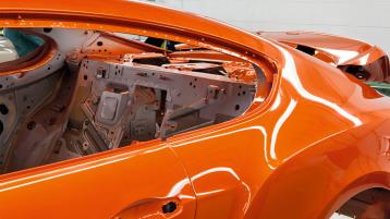 Rear side view of Bentley Continental GT Speed W12 in Orange Flame colour under fabrication process in production line.