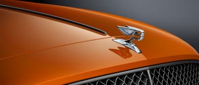 Front view of Bentley Flying Spur Speed in Orange Flame colour featuring Black gloss matrix grille and Illuminated Flying ‘B’ radiator mascot – bright polished stainless steel.