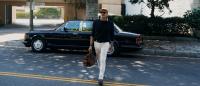 Billy Zane walking away from his Bentley Turbo R, which is parked at the side of the road.