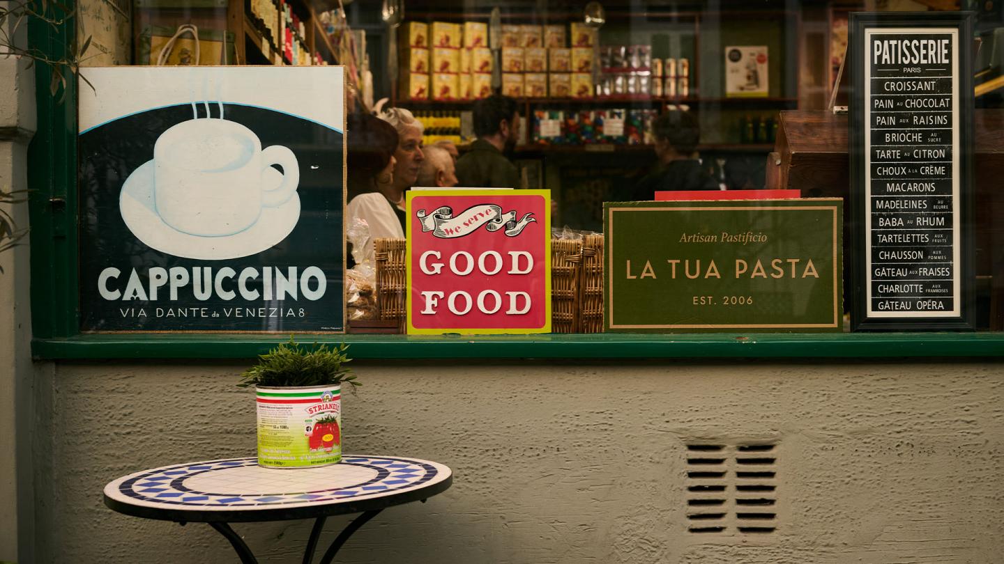 The outside of Salvino's, showing a menu, signs and a small table.