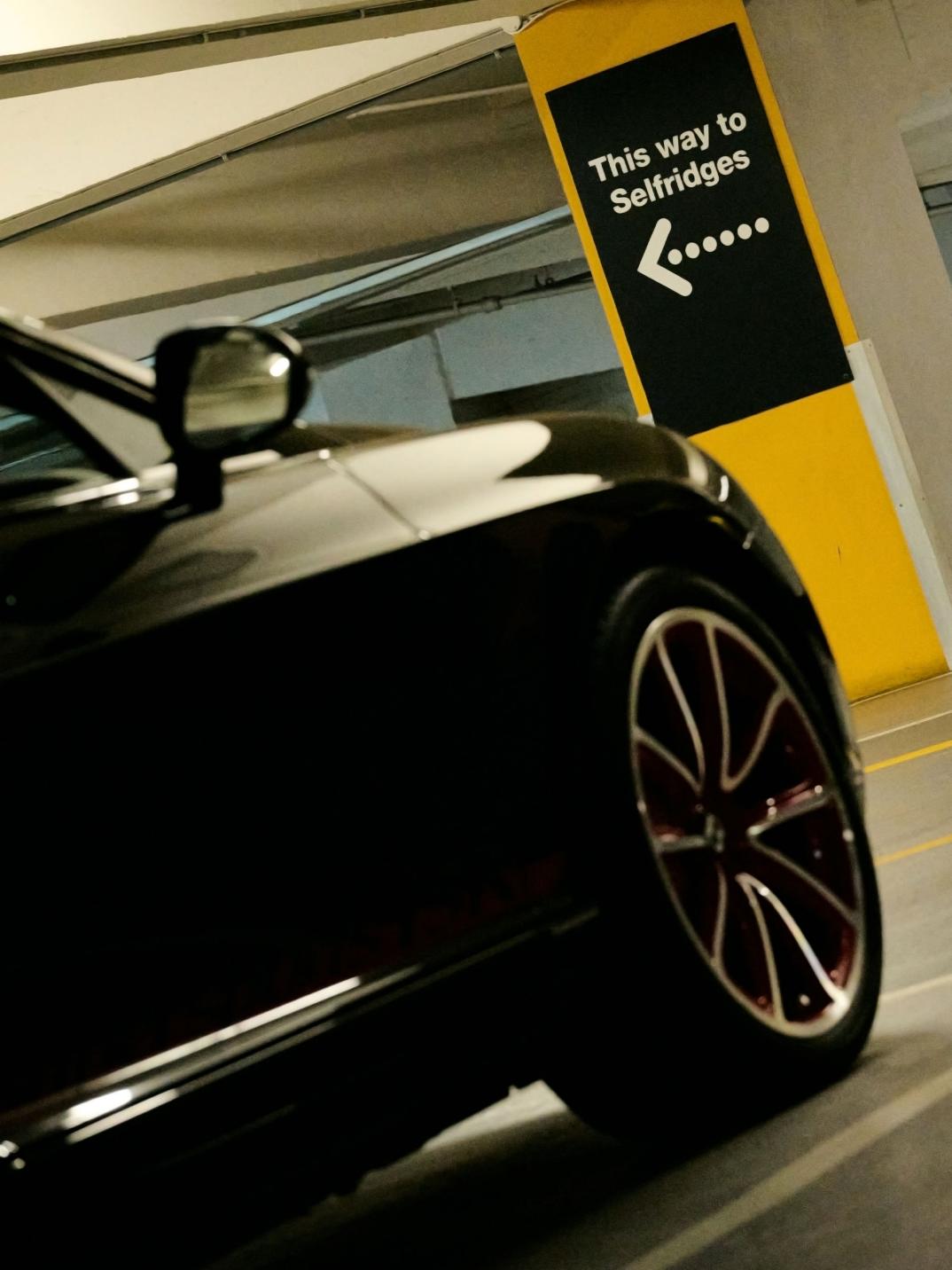 Chart Chirathivat's Bentley Supersports ISR in a covered car park, with a sign to Selfridges in the background.