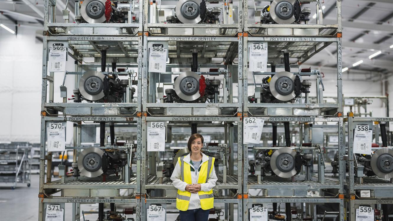Fanny Weiss standing in front of car parts in the logistics warehouse.