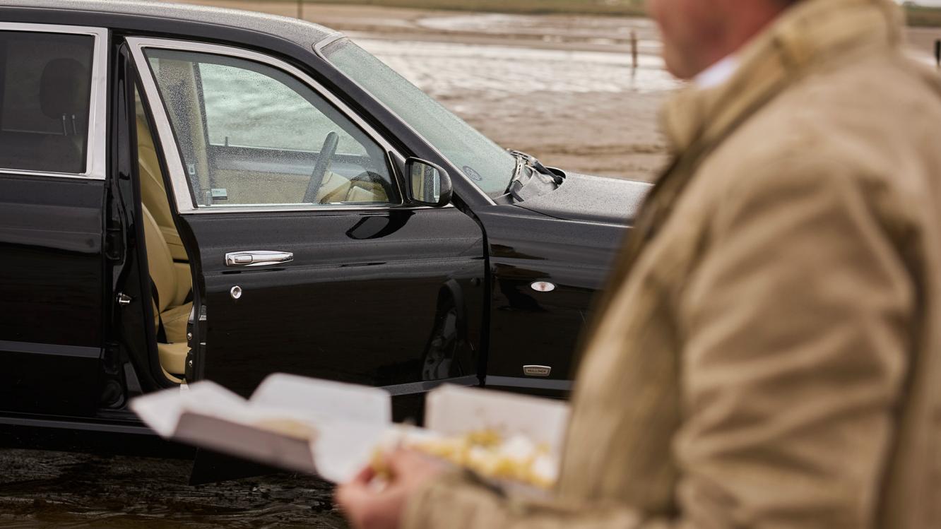 Hubert de Pelet holding fish and chips next to his Bentley Arnage T.