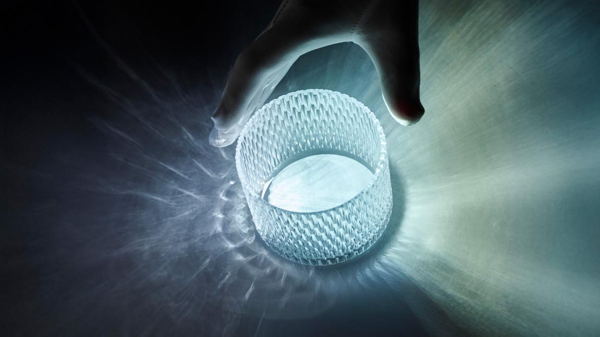 Close up of a gloved hand reaching out to adjust a diamond glass, which light shining though the glass.
