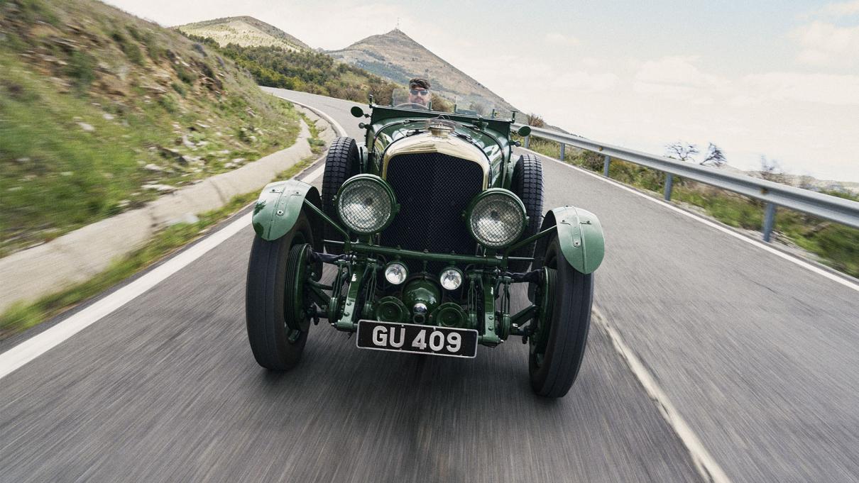 Bentley Speed Six driving, with a mountain in view in the background.