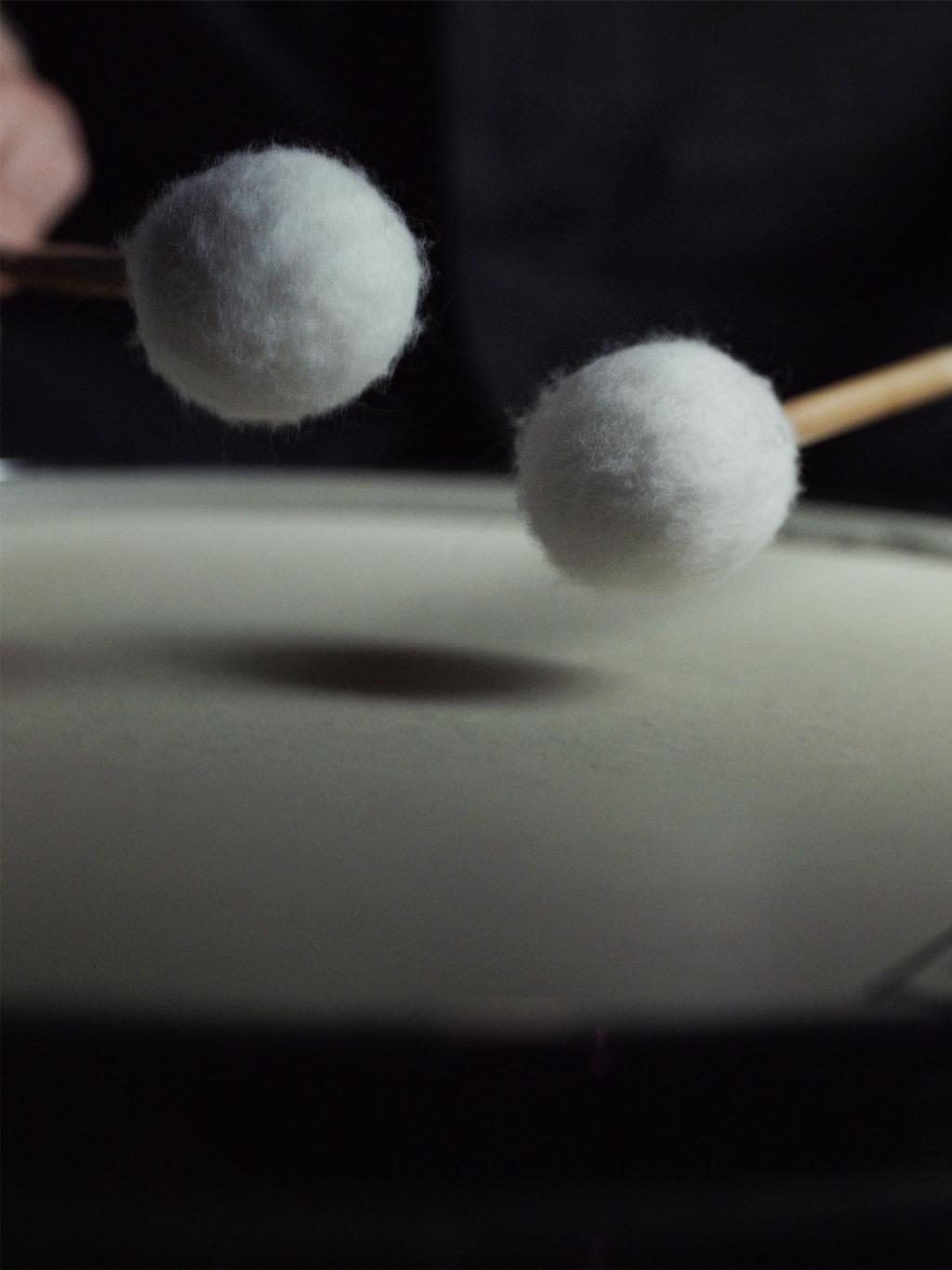 Close up of drumsticks hitting a drum.