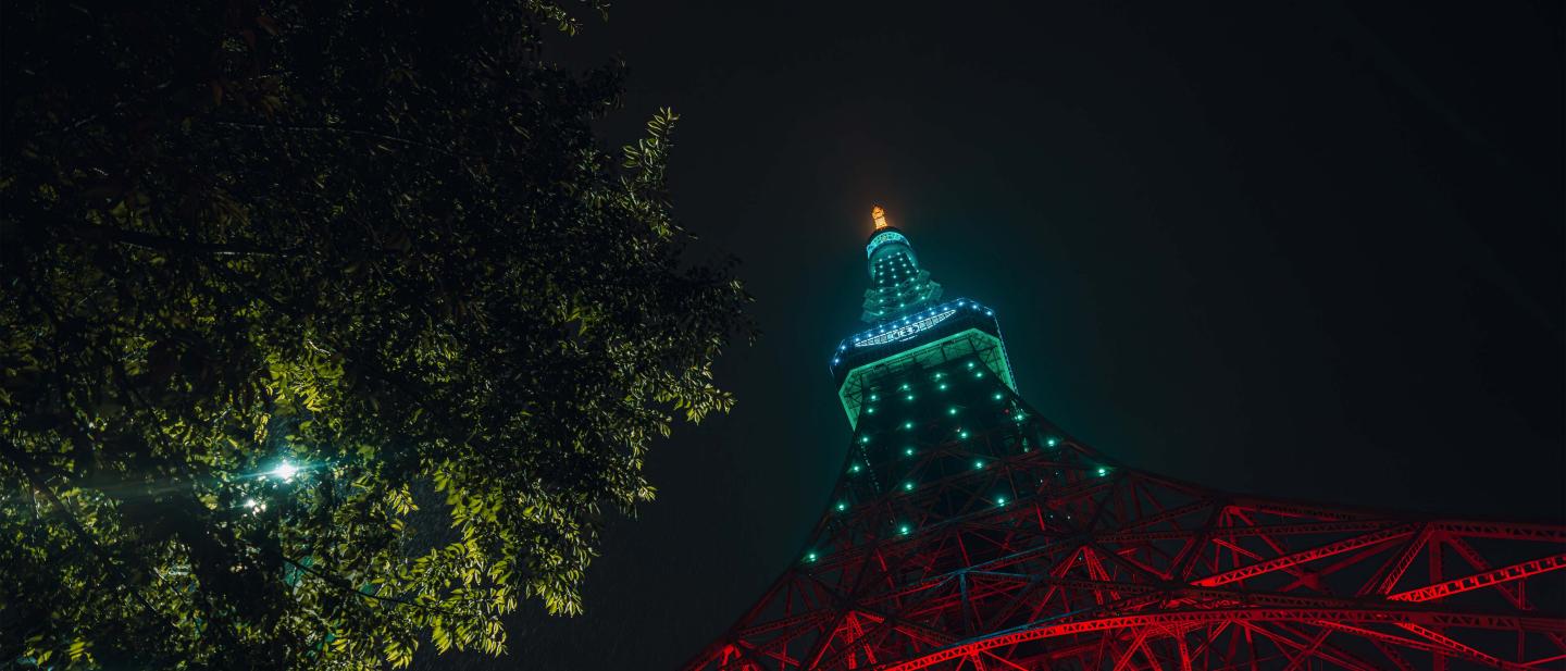 Tokyo Tower lit up green with Bentley logo on the side.