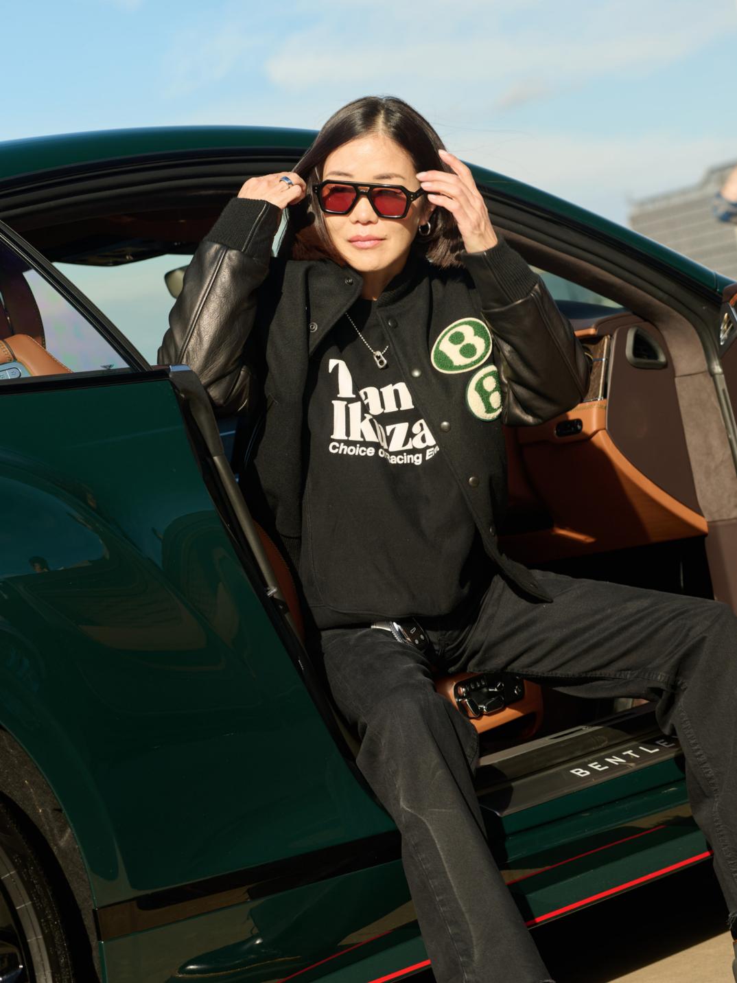 Mai Ikuzawa getting out of the drivers seat of a Bentley Continental GT Speed wearing the 1919 Collection