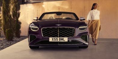 Model walking beside the new hybrid Continental GTC Mulliner with Damson exterior paint  in an urban environment