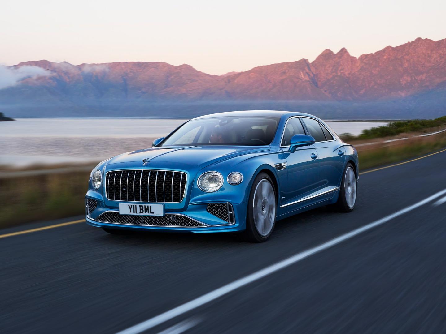 Front three quarter of the new hybrid Bentley Flying Spur Azure in Light Windsor Blue featuring 21 inch diamond cut wheels