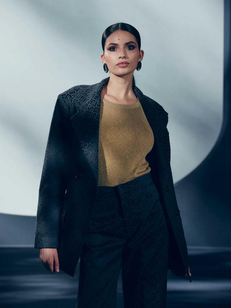 Individual/Woman/Lady dressed in purple diamond textured overcoat posing for a photograph