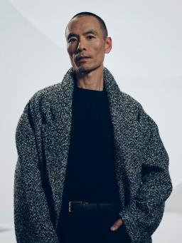 Individual/Man dressed in grey jacket posing for a photograph
