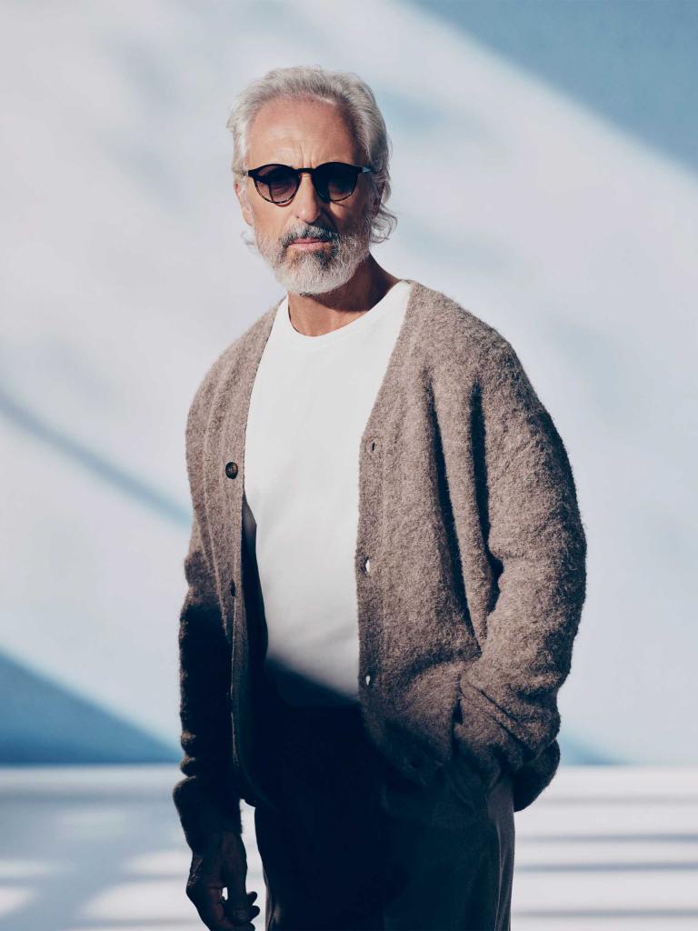 A grey bearded model/ person with sunglasses in white shirt and brown cardigan