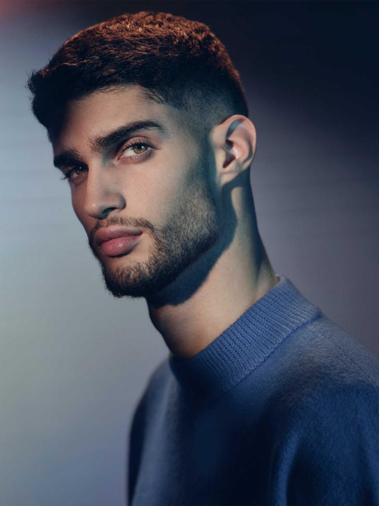 Individual/man/model dressed in blue turtle neck posing for a photograph.