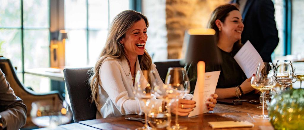 An individual / woman sitting at dinner table, with other people in view at The Macallan Estate in Speyside,Scotland