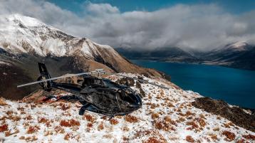 A black tri rotor helicopter parked on a snow covered hill near South Islands of New Zealand.