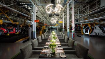 Dining tables and cuttlery laid out with Bentley Production line in view