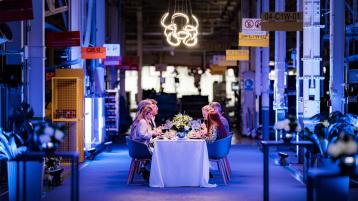 People enjoying dinner at Bentley's factory in Crewe with production line in view.