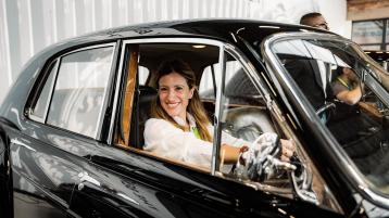 A person/lady/ in driver's seat of Bentley S1 Contental Flying Spur posing for a photograph.