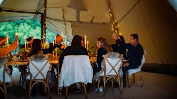 Group of people raising toast over lunch with candle lights as part of Bentley Extra Ordinary Journey UK