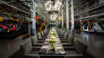 Dining tables and cuttlery laid out with Bentley Production line in view