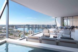 Bentley Residence Miami, with reclining chairs on terrace overlooking water bodies around Sunny Isles Beach and high rise buildings. 
