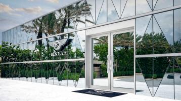 Exterior view of Bentley residences sales gallery, with diamond shaped glass exterior and Bentley Flying Wings badge on front.
