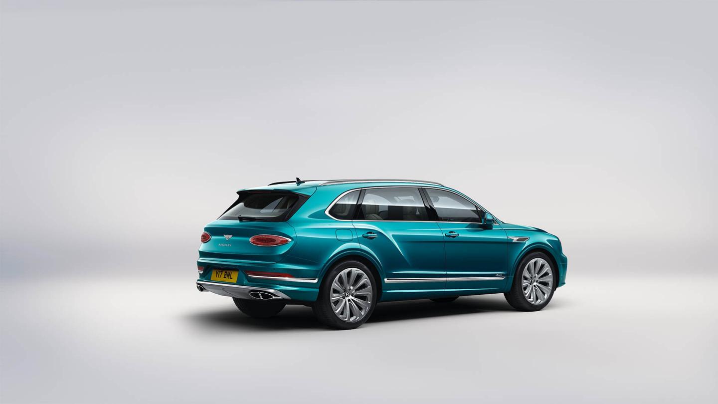 Rear side angled view of Bentley Bentayga EWB Azure in Topaz Blue colour featuring featuring 22 inch ten spoke wheel - Painted and sculpted elliptical tail lamps.