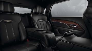 Rear passenger seat view of Bentley Bentayga EWB featuring Beluga hide and contrast stitching of Bentley emblem in Linen.