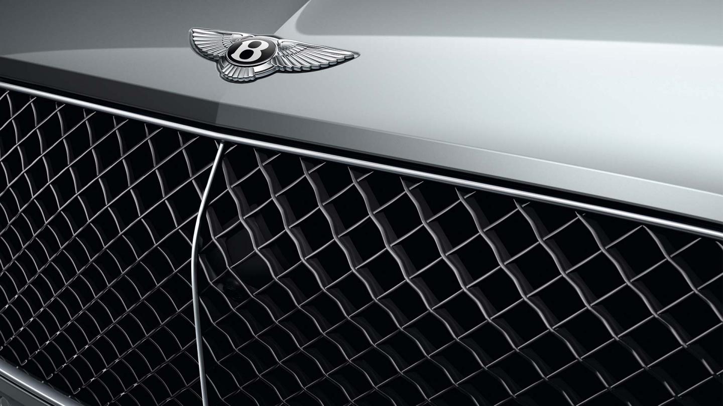 Front quarter close view of Bentley Bentayga EWB in Moonbeam colour, featuring Black radiator matrix grille with bright surround and Bentley Wing Badge.