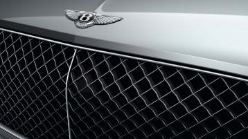 Front quarter close view of Bentley Bentayga EWB in Moonbeam colour, featuring Black radiator matrix grille with bright surround and Bentley Wing Badge.