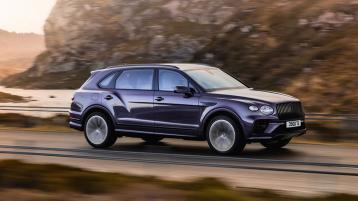 Bentley Bentayga EWB Mulliner in Tanzanite Purple colour side angled view, driving on road with mountains in backdrop.