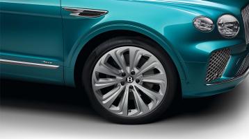  Side one quarter view of Bentley Bentayga Azure EWB in Topaz blue with chrome accents and Azure emblem in focus with 22 inch Ten Spoke Wheel.